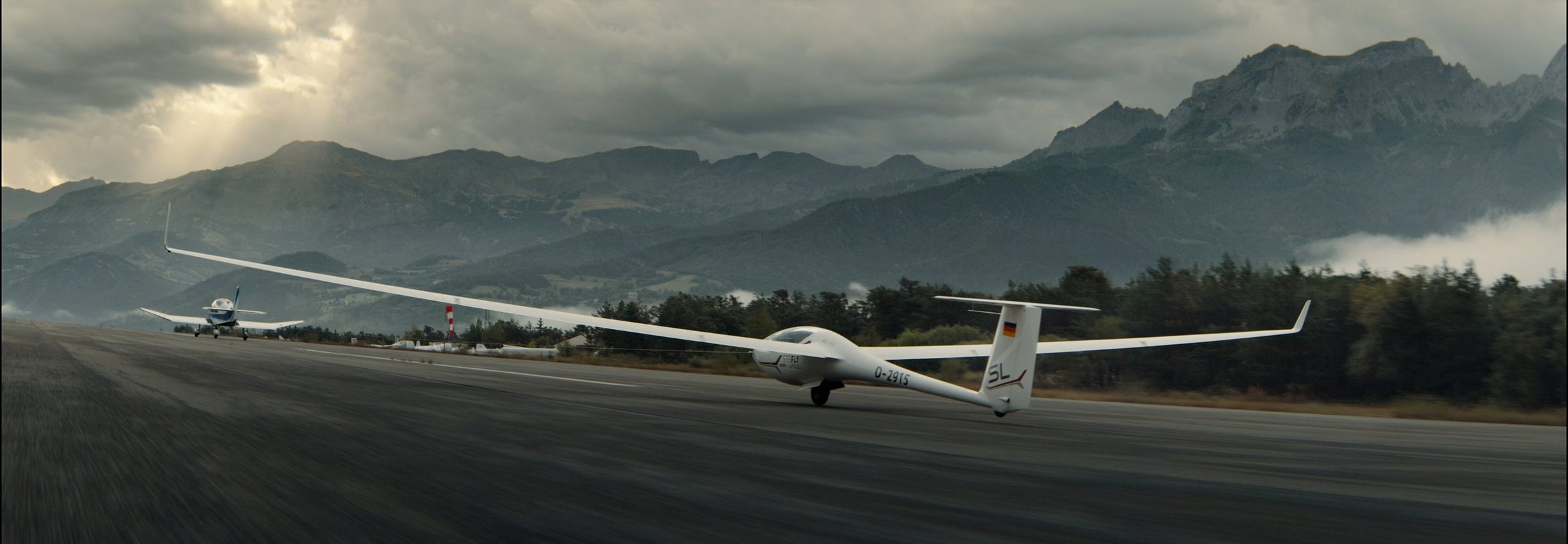 A glider on a mountain runway under heavy cloud