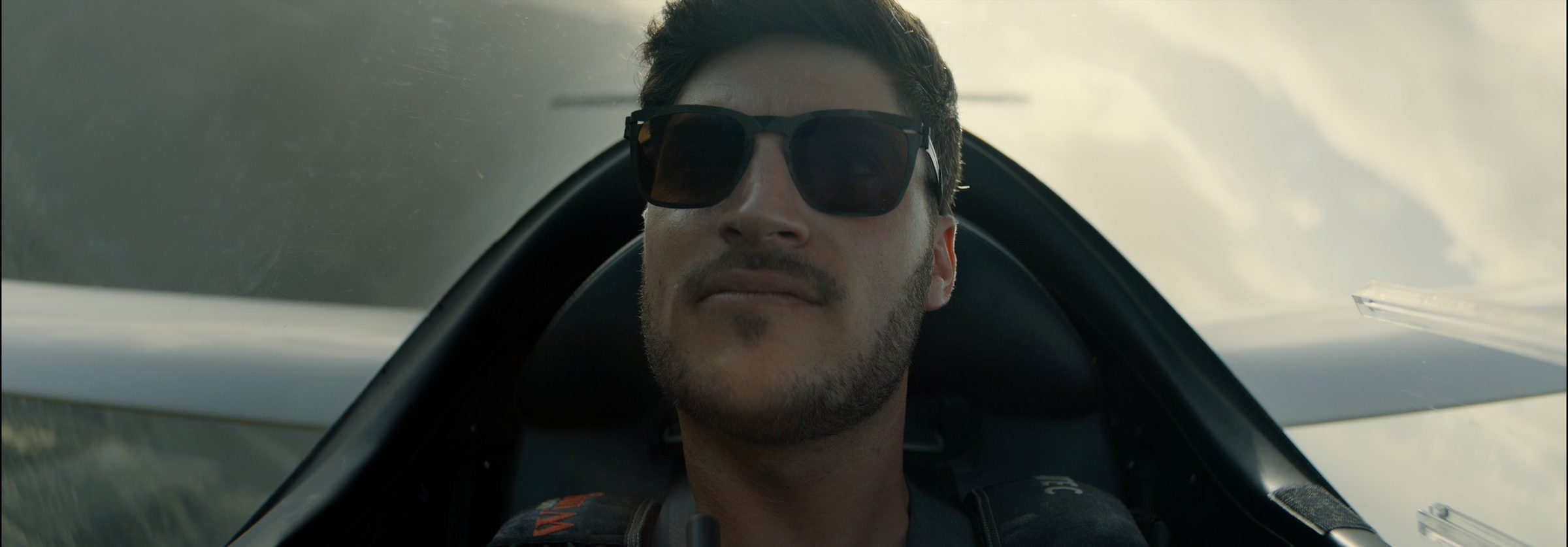 A pilot in sunglasses in the cockpit