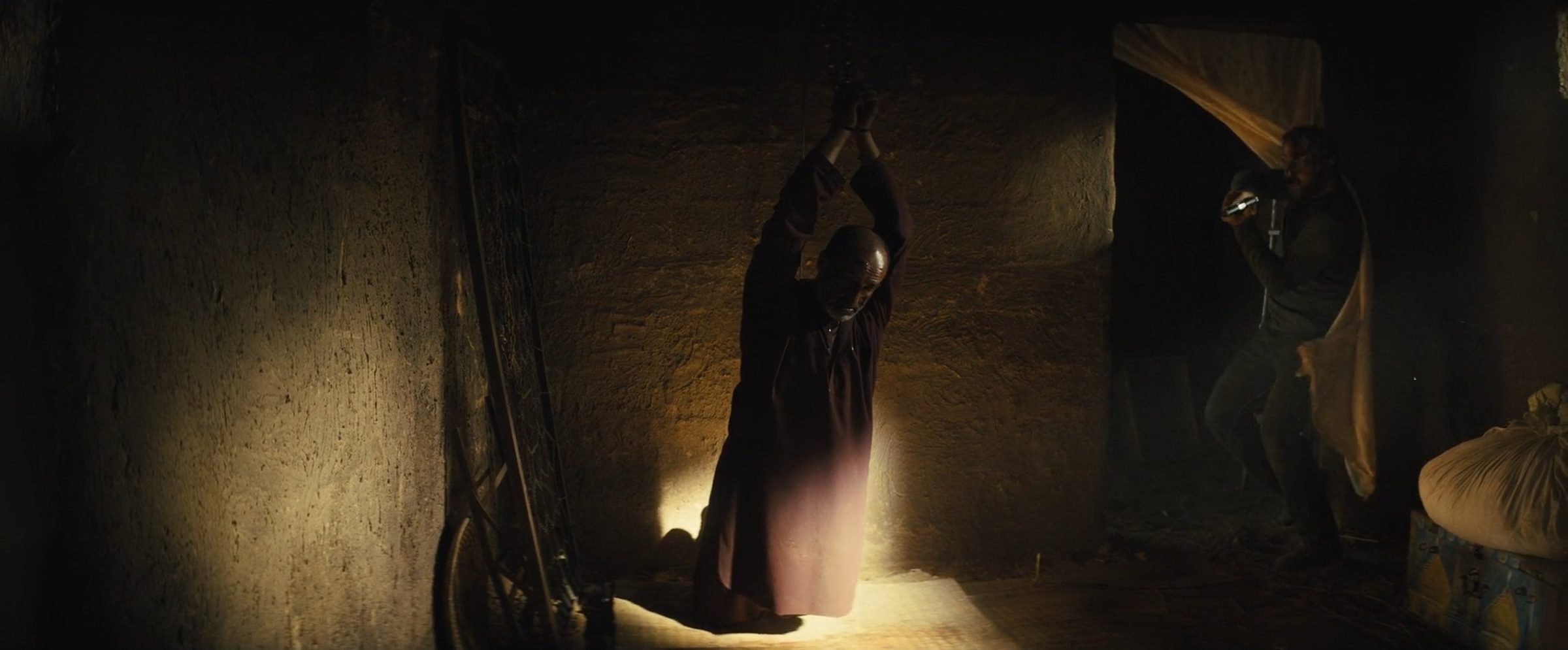 A woman at prayer in a shaft of light in a stone room